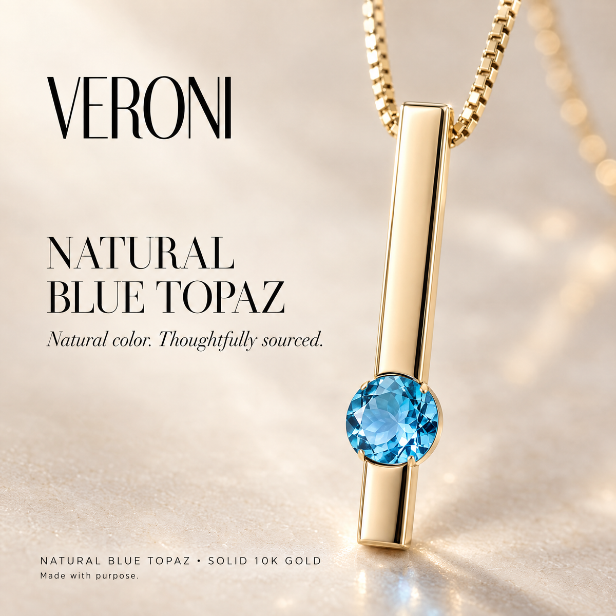 Yellow Gold Concetta natural blue topaz pendant on a warm ivory background in a VERONI campaign.