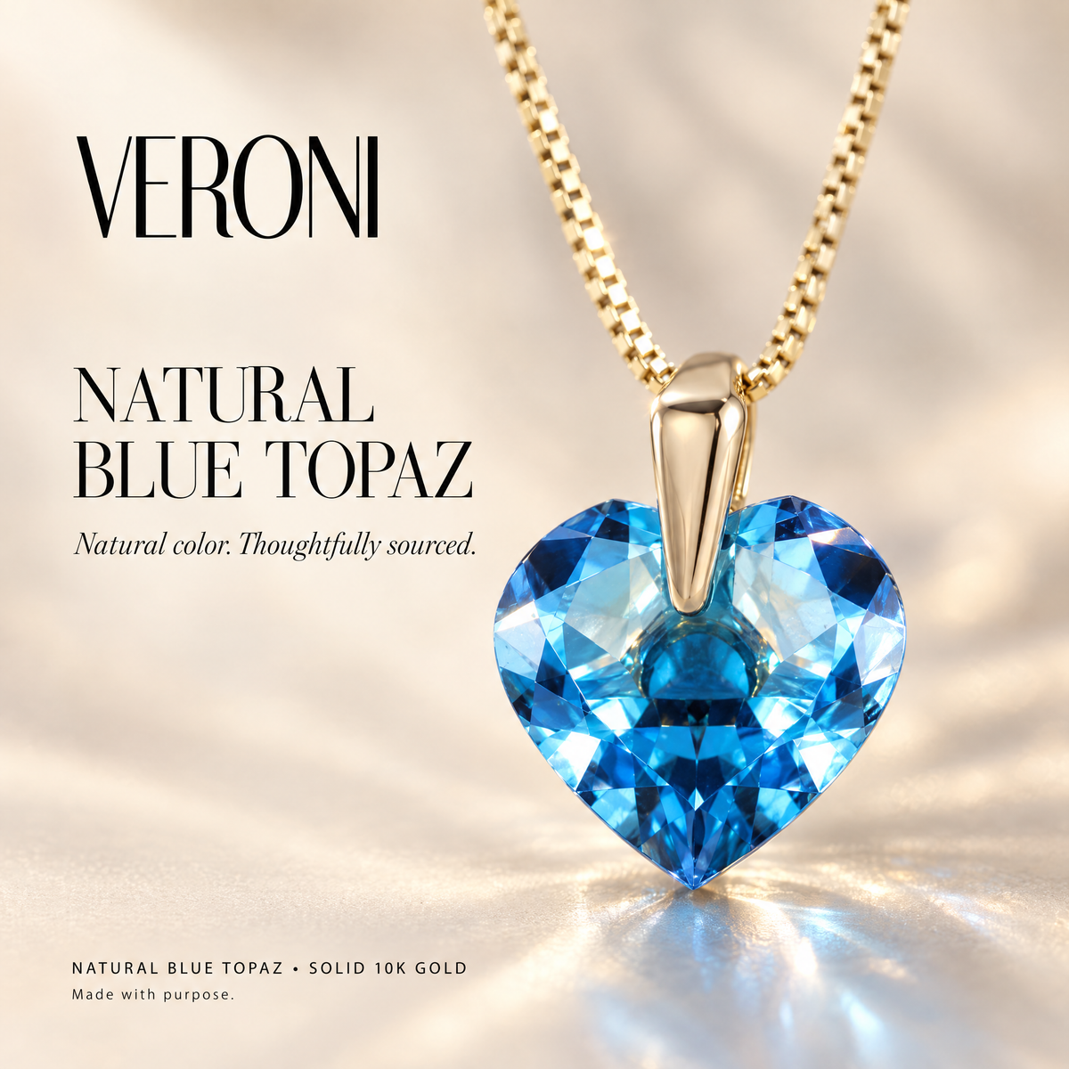 Yellow Gold Rosalia natural blue topaz pendant on a warm ivory background in a VERONI campaign.