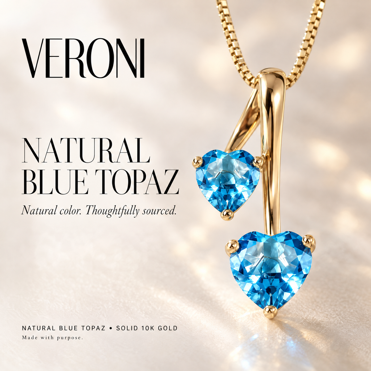 Yellow Gold Berenice natural blue topaz pendant on a warm ivory background in a VERONI campaign.