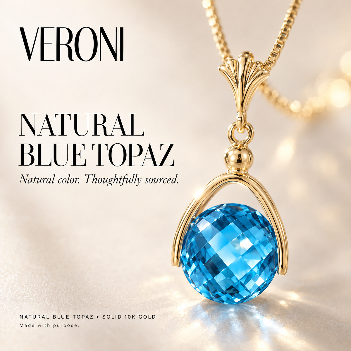 Yellow Gold Benedetta natural blue topaz pendant on a warm ivory background in a VERONI campaign.