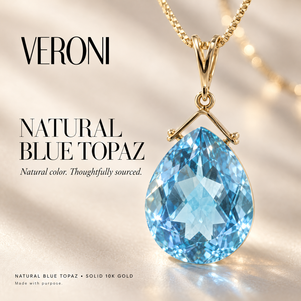 Yellow Gold Chiara natural blue topaz pendant on a warm ivory background in a VERONI campaign.