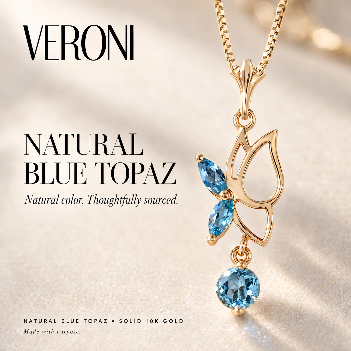 Yellow Gold Fausta natural blue topaz pendant on a warm ivory background in a VERONI campaign.