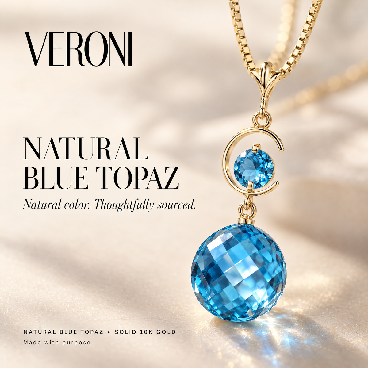 Yellow Gold Evelina natural blue topaz pendant on a warm ivory background in a VERONI campaign.