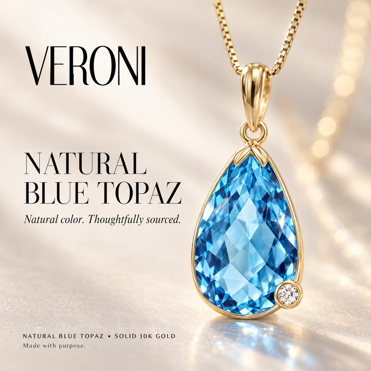 Yellow Gold Gaudenzia natural blue topaz pendant on a warm ivory background in a VERONI campaign.